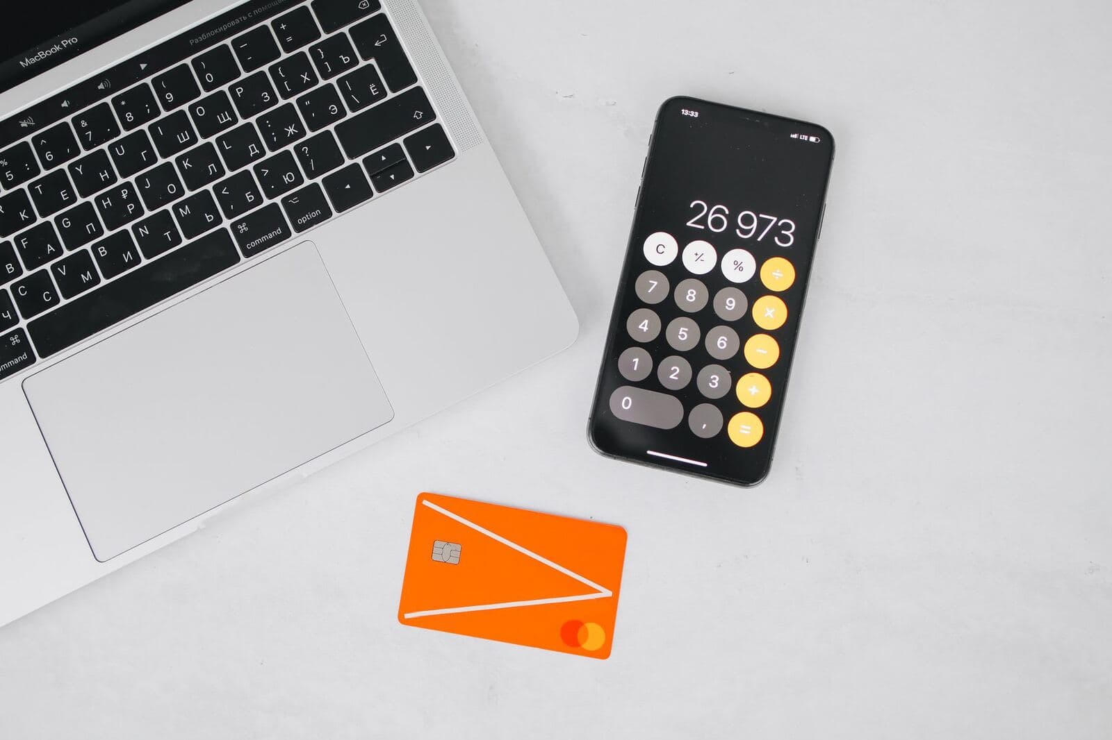 Person reviewing finances with a calculator, cards and laptop